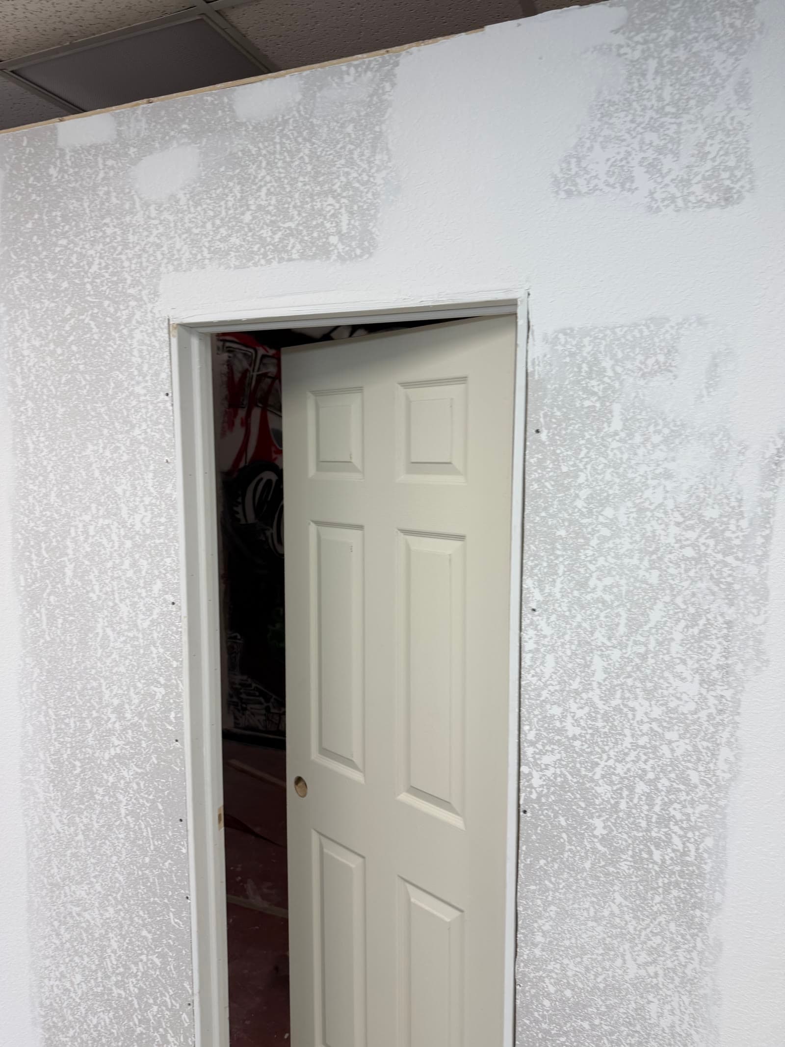 Textured drywall and installed door during the Exodus Barbershop room project