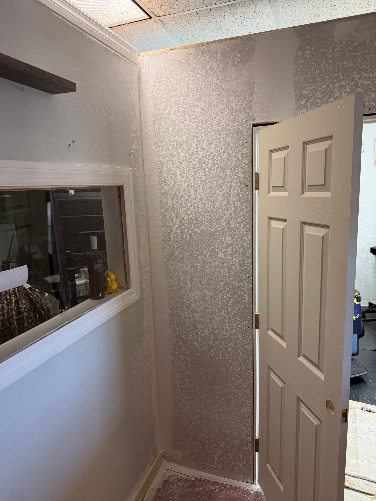 Textured walls with door and window trim in progress at a Palm Bay barbershop